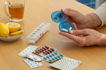 Daily medication organization with pill box and tablets on wooden table. Health care
