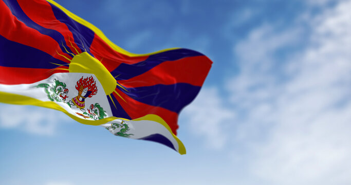 Tibetan flag waving outdoors with snow lions and rising sun symbolizing freedom