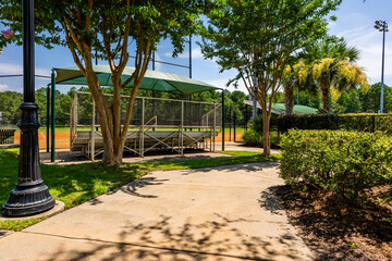 Empty bleachers at a softball field on a sunny day in a peaceful park environment with surrounding...