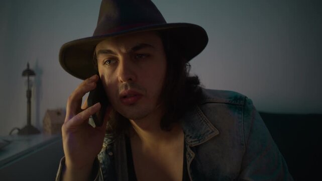 Handsome modern cowboy in hat talking on the phone