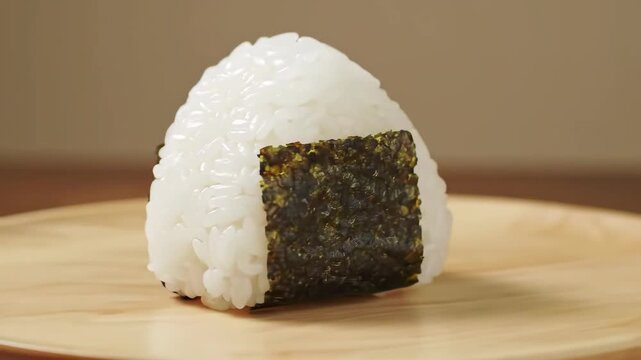 Close-up of a single onigiri rice ball with nori seaweed on a wooden plate