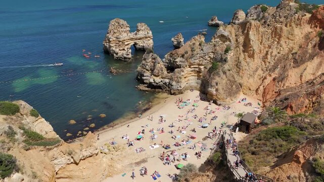 Aerial view of people enjoying the European summer at the famous Praia do Camilo beach in Lagos, Algarve region, Portugal.
