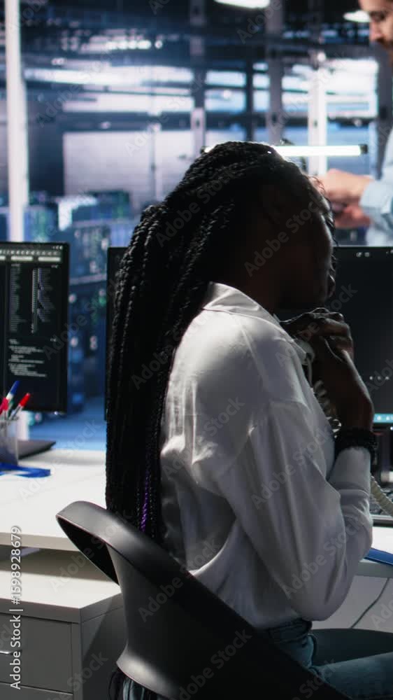 Poster vertical video female technician in data center answers telephone call, assisting users with ai trou