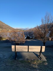 Sun hitting park bench with mountain views on blue sky day, cold winter frosty morning