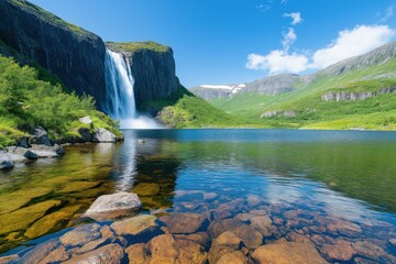 Breathtaking Waterfall Cascading into a Tranquil Lake Surrounded by Majestic Green Hills and Clear Blue Skies, Perfect for Nature Enthusiasts and Photographers