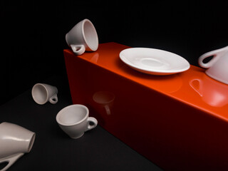 Several white ceramic cups and plate are arranged on a brown wooden surface.