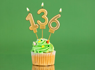 Number 136 birthday candle - Cupcake on a green background