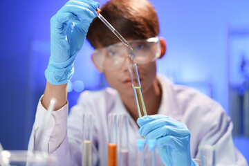 Scientists working in Laboratory using pipette dropping liquid sample into test tube.