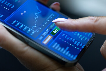 Woman buys shares online on her smartphone, prices, stock market information. Internet trading,...