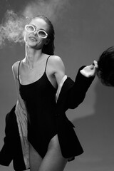 black and white smiling woman wearing sunglasses and jacket with smoke around her in casual stylish...