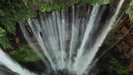 Aerial view of majestic waterfall cascading through lush green forest