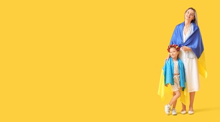 Cute little girl and her mother with Ukrainian flags on yellow background with space for text