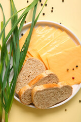 Plate of tasty processed cheese with bread and scallions on orange background