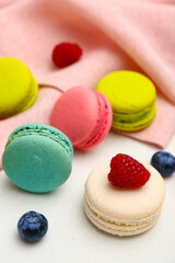 Sweet macaroons and berries on white background