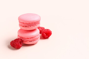Tasty sweet macaroons and raspberries on pink background