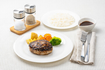 白いテーブルにハンバーグとライスの洋食セット