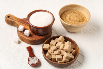 Bowls different types of sugar on white background