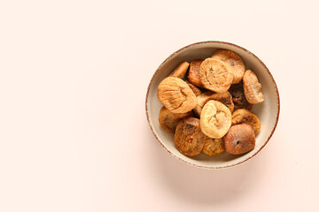 Bowl with sweet dried figs on beige background
