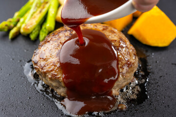 鉄板で焼いたハンバーグにデミグラスソースをかける瞬間