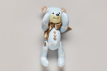 Toy bear with taped mouth and word HELP on light background. Domestic violence concept
