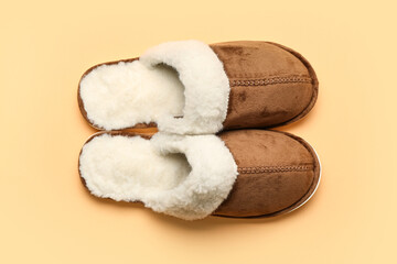 Pair of brown soft slippers on beige background. Top view