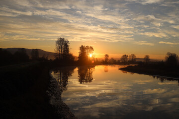 Colorful sunrise with clouds reflected in the river