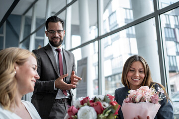 Businessman congratulating female colleagues with bouquet of flowers