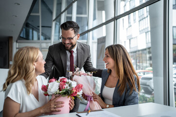 Managers giving flowers to female colleagues in office