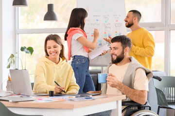Male designer with coffee cup and his colleague working at office