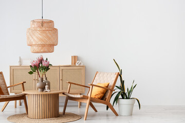 Protea flowers in vase on coffee table and armchairs in interior of living room