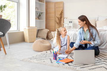 Nanny with cute little girl studying in bedroom