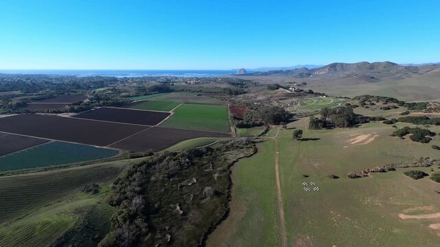 A forward aerial view over the Los Osos Creek Wetland Preserve near San Luis Obispo, California. The Pacific Ocean and Morro Rock in the distance. Helicopter GoPro footage. Longer segments available.