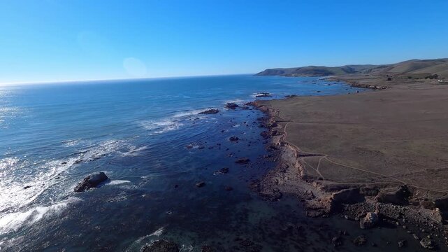 A low flyover of the rocky Pacific shoreline. Estero Bay and Cayucos Point below. Helicopter GoPro footage. Longer segments available upon request.  	