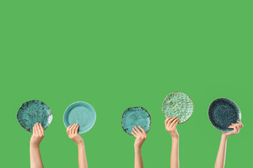 Female hands with plates on green background