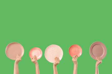 Young women holding different plates on green background