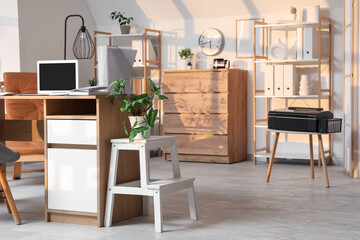 Interior of office with workplace, shelf units and plants