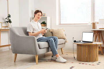 Teenage boy with laptop, headset and mobile phone working online at home