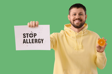 Young man holding paper with text STOP ALLERGY and orange on green background
