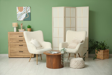 Interior of modern room with folding screen, armchairs and table