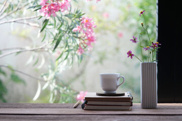 White ceramic coffee cup and delicate pink flowers in a white vase with pink flowers background