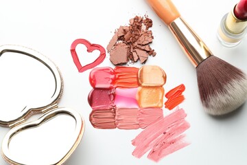 Different cosmetic products, mirror and makeup brush on white background, flat lay