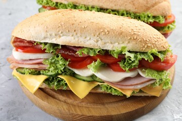 Tasty baguette sandwiches with ham, cheese and vegetables on grey textured table, closeup