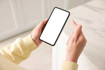 Woman using modern smartphone at home, above view