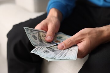 Man counting his money indoors, closeup view