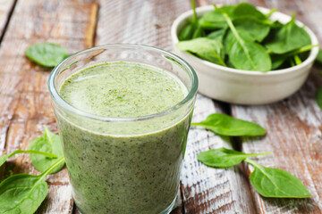 Tasty smoothie and spinach leaves on wooden table, closeup