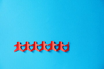 Paper figures of people holding hands on light blue background, top view. Space for text