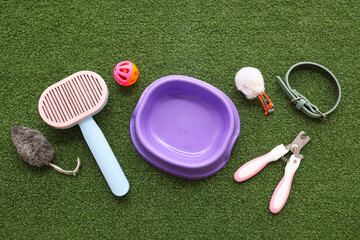 Food bowl and different pet accessories on green grass background
