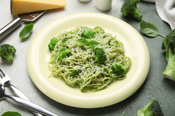 Plate of delicious spaghetti pasta with broccoli, cheese and basil leaves on grunge background, closeup
