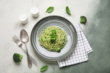 Plate of delicious spaghetti pasta with broccoli and basil leaves on grunge background
