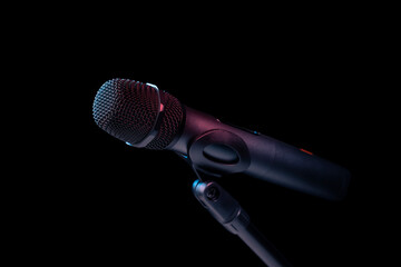 Close-up of microphone in studio or concert performance on stage, on black background.